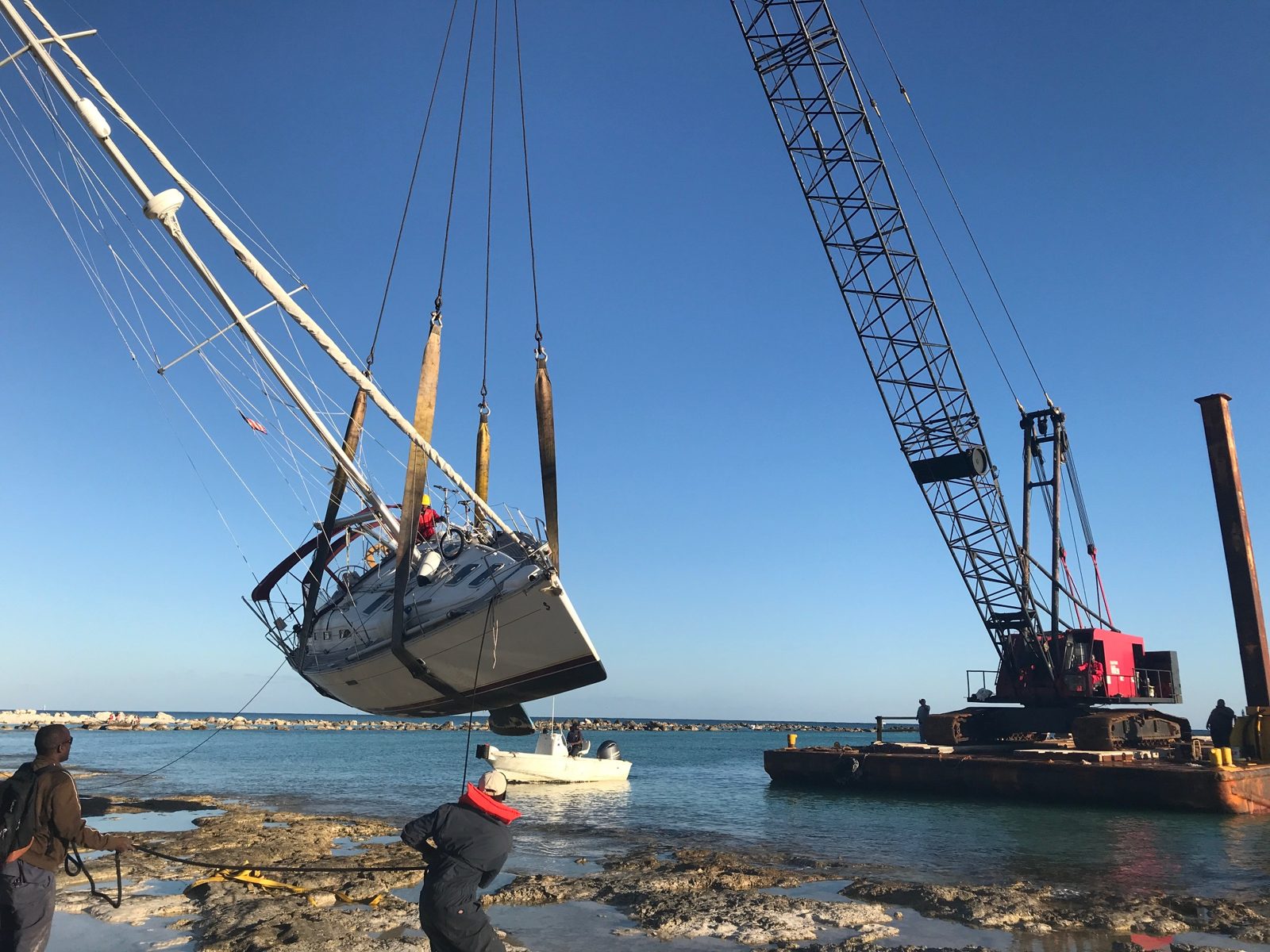 Salvaged sailboat lifted by crawler crane